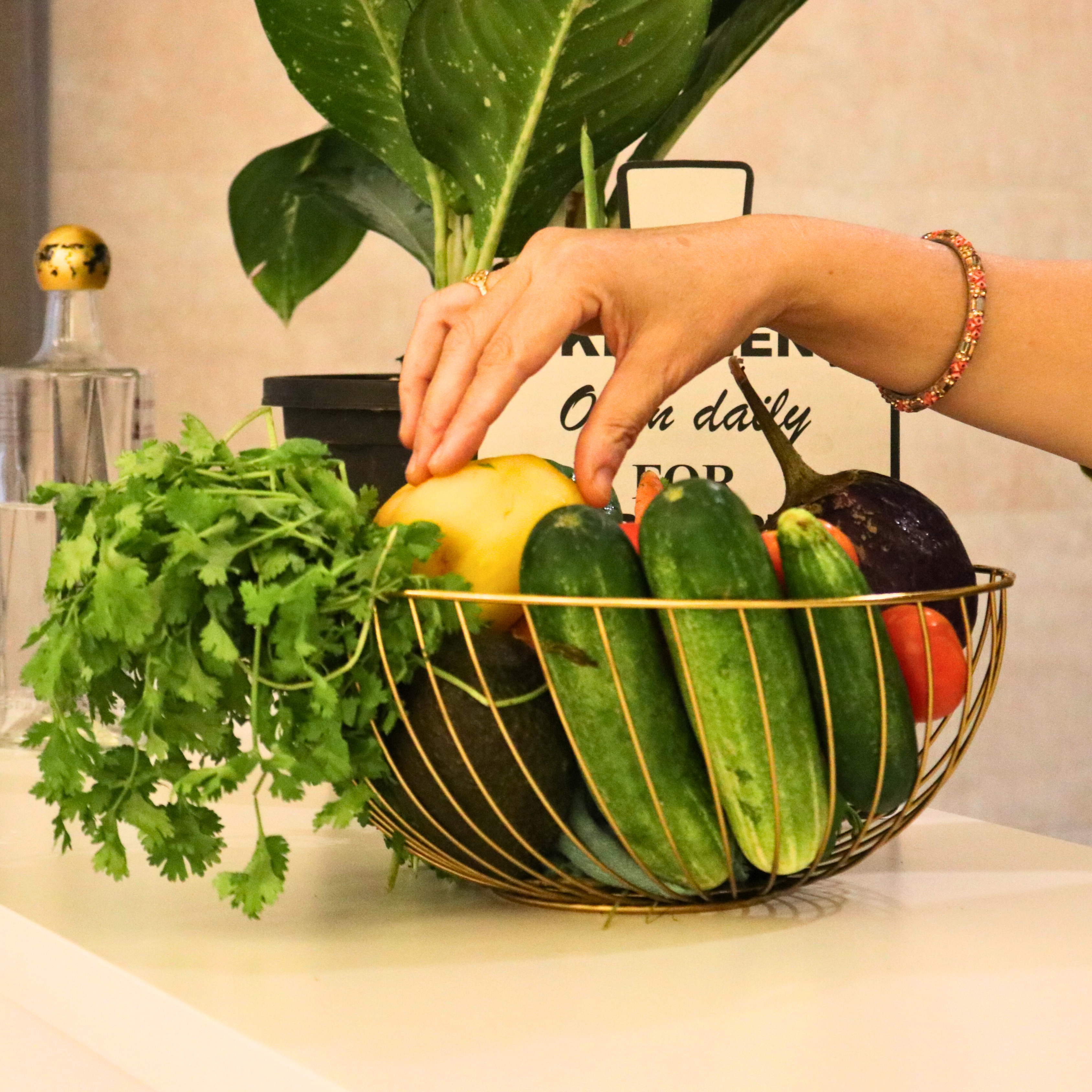 Gold Electroplated Spiro Iron Fruit Basket elegantly styled on a kitchen countertop with assorted vegetables