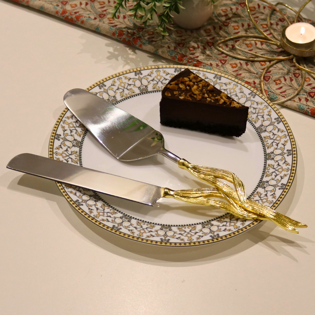 Golden Maize Leaf Cake Server Set with stainless steel blades and maize leaf-inspired handles, elegantly placed on a decorative plate with a slice of chocolate cake